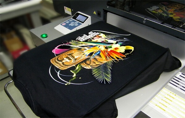 Screen printing machine producing a full colour graphic on a black t shirt